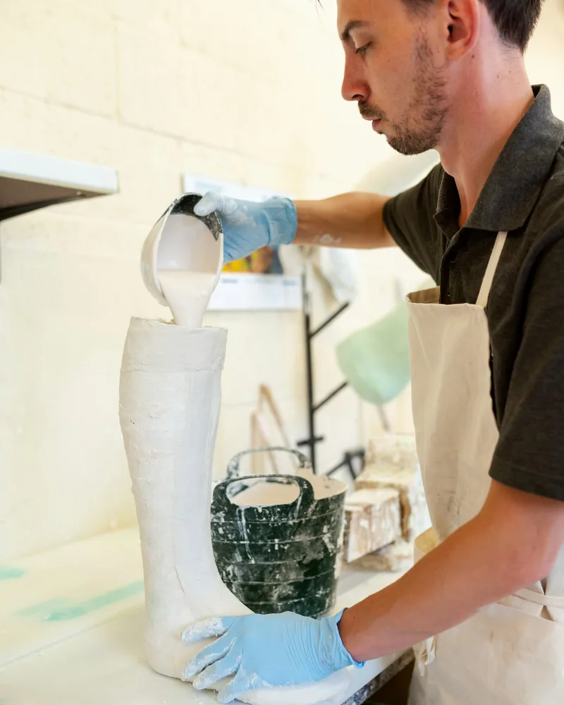 Impasto di gesso versato lentamente dentro una forma verticale in un laboratorio di formatura