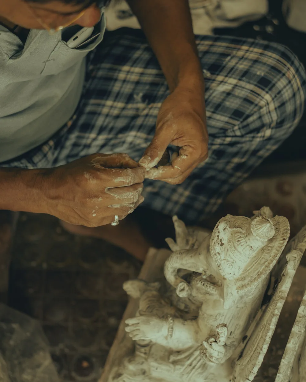 Mani che rifiniscono un rilievo in gesso appena estratto dalla forma, sul piano di lavoro di un laboratorio